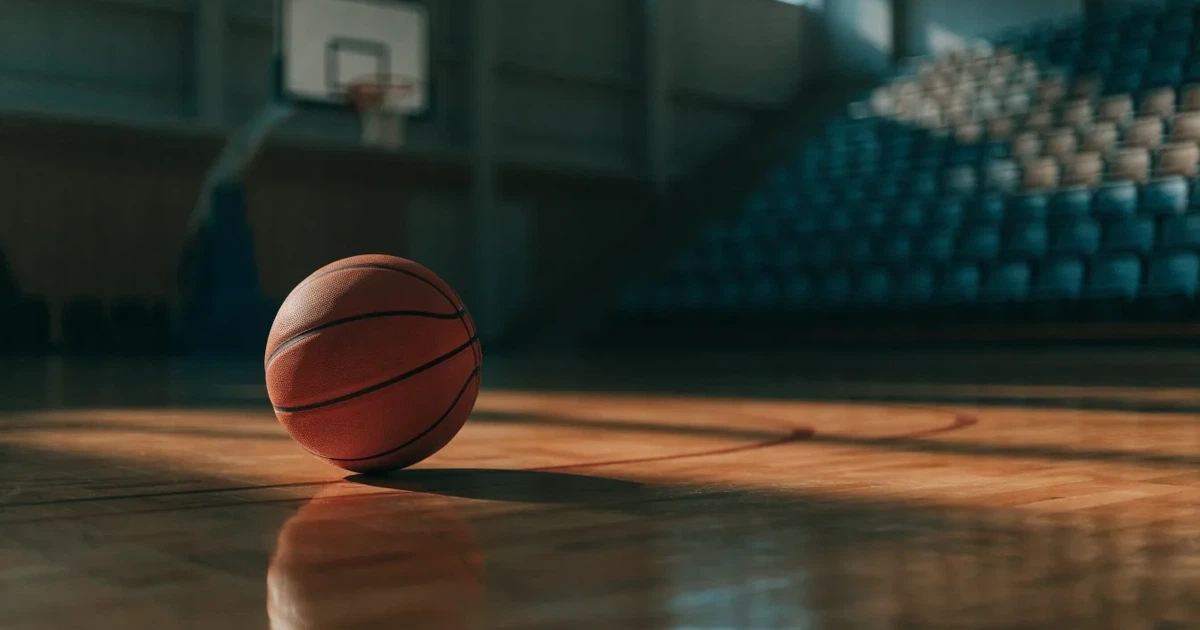 Uma bola de futebol no ponto central de um relvado, à luz da manhã
