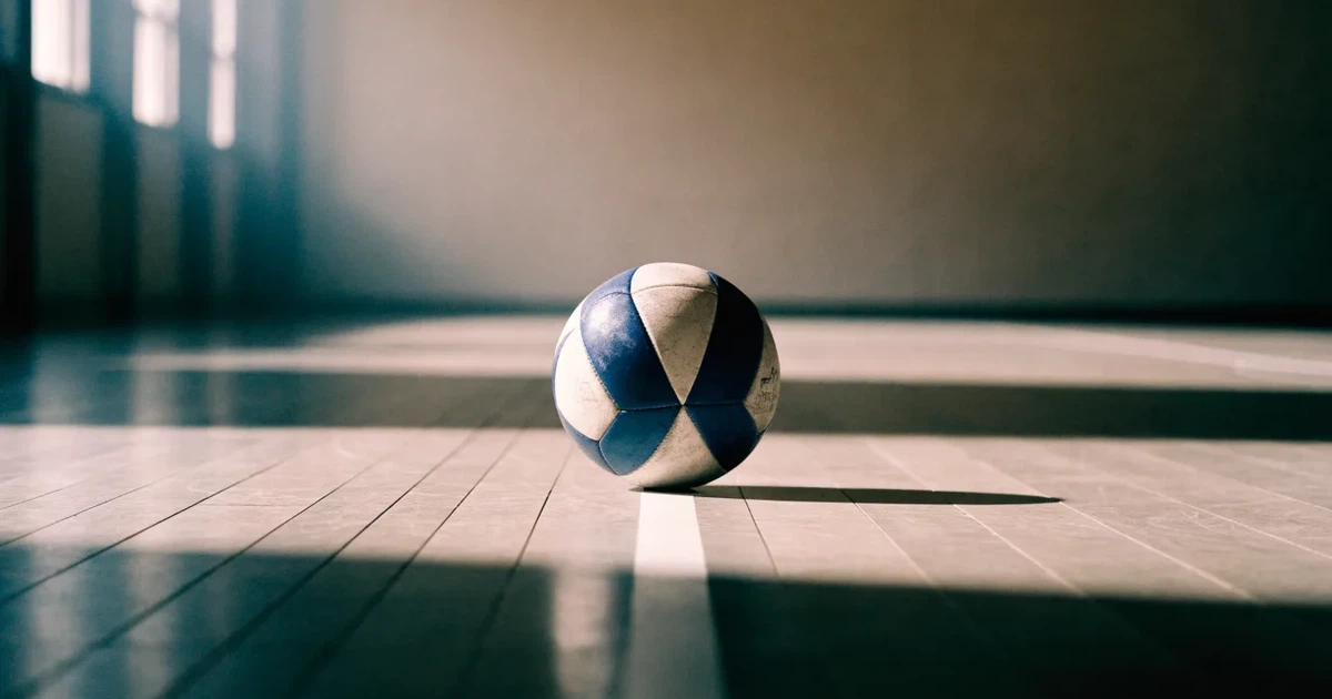 Uma bola de futebol no ponto central de um relvado, à luz da manhã